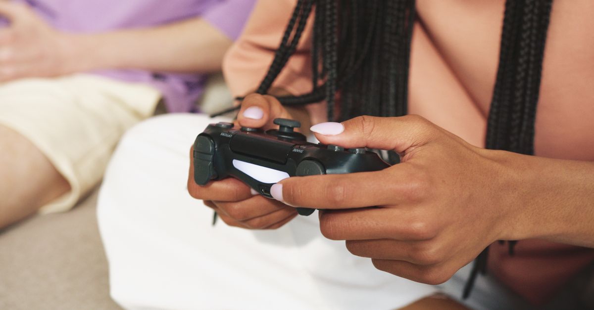 Person holding a wireless gaming controller, focused on the screen